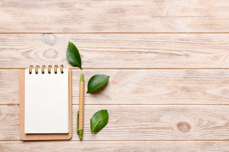 eco-friendly Empty notebook with pen and green leaf on Colored background for note.