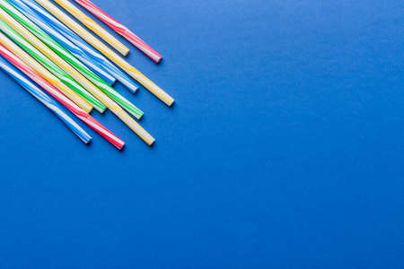 Heap of colorful plastic drinking straws on Colored background, flat lay. Copy Space for text.の写真素材