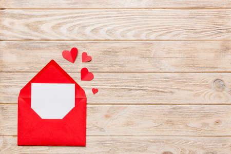 Red paper envelope with empty white card and heart on colored background. top view valentines day concept.の写真素材