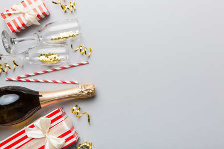 Bottle of champagne with colored glitter, confetti and gift box space for text on colorfull background, top view. Hilarious, christmas and birthday celebration.の写真素材