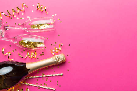 Champagne bottle, glitter and straws on color background. top view. Hilarious, christmas and birthday celebration.の写真素材