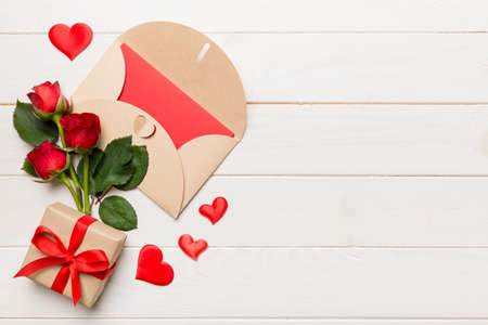 Valentine day composition with envelope, rose flower and red heart on table. Top view, flat lay,...