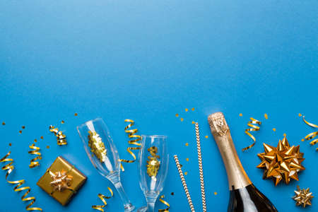 Bottle of champagne with colored glitter, confetti and gift box space for text on colorfull background, top view. Hilarious, christmas and birthday celebration.の写真素材