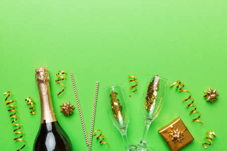 Bottle of champagne with colored glitter, confetti and gift box space for text on colorfull background, top view. Hilarious, christmas and birthday celebration.の写真素材