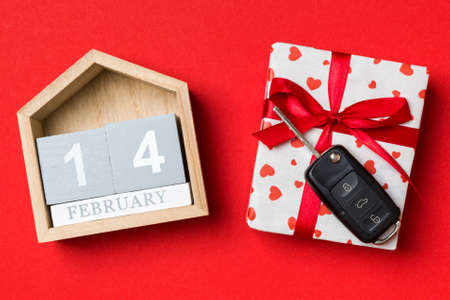 Top view of car key on a gift box with red hearts and festive calendar on colorful background. The fourteenth of february. Present for Valentine's Day concept.の写真素材