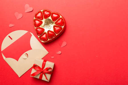 Envelope on colored background for Valentine Day with gift box and chocolate. Heart shaped with gift box of chocolates top view with copy space.の写真素材