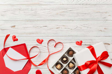 Envelope on colored background for Valentine Day with gift box and chocolate. Heart shaped with gift box of chocolates top view with copy space.の写真素材