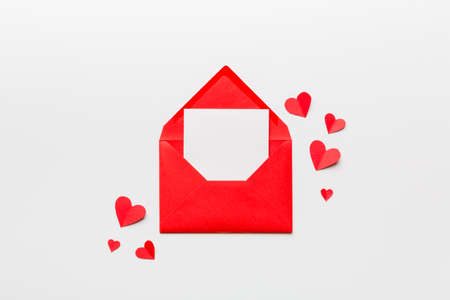 Red paper envelope with empty white card and heart on colored background. top view valentines day concept.の写真素材