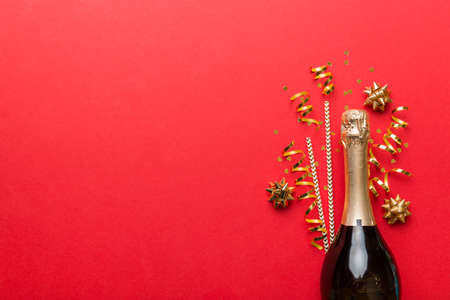 bottle of champagne with glasses and colorful confetti on colored background. top view flay lay.