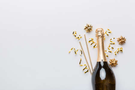 bottle of champagne with glasses and colorful confetti on colored background. top view flay lay.