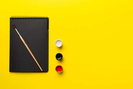 Album pages and paints, pencils, brush on a colored background. Top view with empty space. workplace...