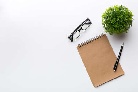 Modern office desk table with notebook and other supplies with green tree. Blank notebook page for you design. Top view, flat lay.の写真素材