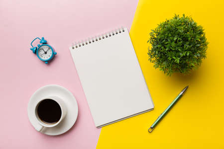 Modern office desk table with notebook and other supplies with cup of coffee. Blank notebook page...