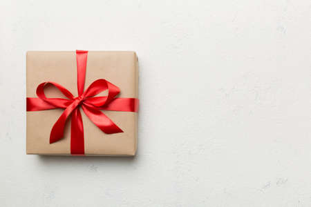 Holiday gift box wrapped in craft paper with colored bow on table background. Top view, flat lay, copy space.の写真素材