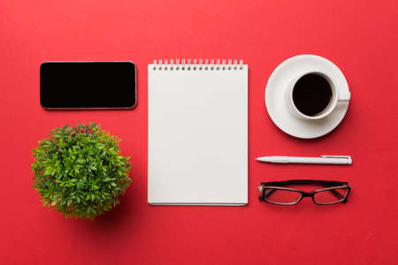 Modern office desk table with notebook, smartphone and other supplies with cup of coffee. Blank notebook page for you design. Top view, flat lay.の写真素材