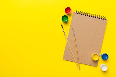 Album pages and paints, pencils, brush on a colored background. Top view with empty space. workplace for creativity. home teaching concept drawing.の写真素材