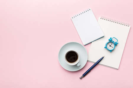 Modern office desk table with notebook and other supplies with cup of coffee. Blank notebook page...