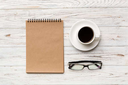 Modern office desk table with notebook and other supplies with cup of coffee. Blank notebook page...