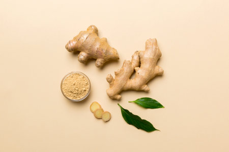 Finely dry Ginger powder in bowl with green leaves isolated on colored background. top view flat lay.の写真素材