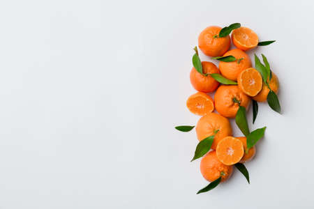 Many fresh ripe mandarin with green leaves on colored background, top view, space for text.の写真素材