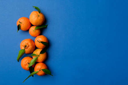Many fresh ripe mandarin with green leaves on colored background, top view, space for text.の写真素材