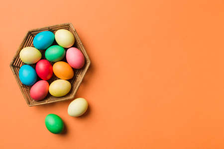 Multi colors Easter eggs in the woven basket on colored background . Pastel color Easter eggs....