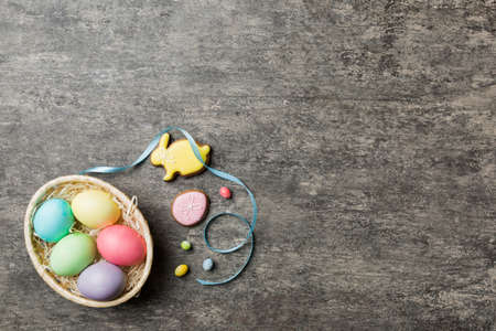 Colorful easter cookies in basket with Multi colors Easter eggs on colored background . Pastel color Easter eggs. holiday concept with copy space.の写真素材