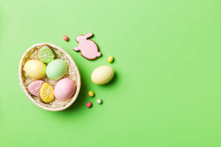 Colorful easter cookies in basket with Multi colors Easter eggs on colored background . Pastel color...
