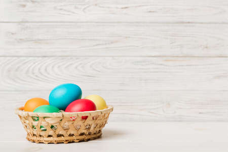 Multi colors Easter eggs in the woven basket on colored background . Pastel color Easter eggs....