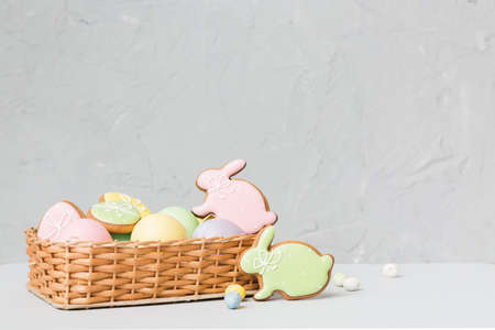 Colorful easter cookies in basket with Multi colors Easter eggs on colored background . Pastel color Easter eggs. holiday concept with copy space.の写真素材