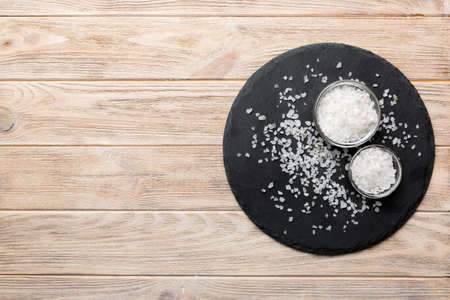 A wooden bowl of salt crystals on a wooden background. Salt in rustic bowls, top view with copy space.の写真素材