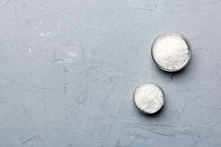 A wooden bowl of salt crystals on a wooden background. Salt in rustic bowls, top view with copy space.の写真素材