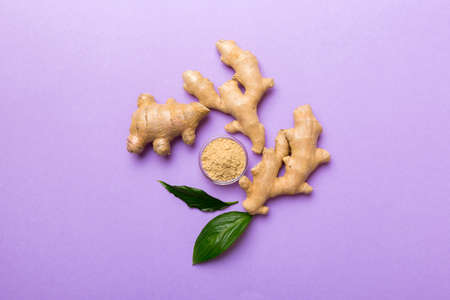 Finely dry Ginger powder in bowl with green leaves isolated on colored background. top view flat lay.の写真素材