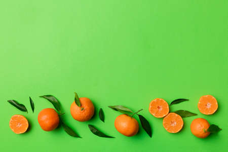 Many fresh ripe mandarin with green leaves on colored background, top view, space for text.の写真素材