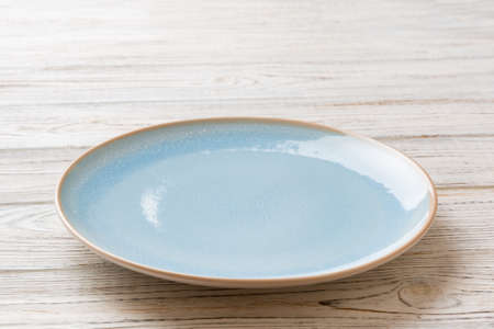 Perspective view of empty blue plate on wooden background. Empty space for your design.の写真素材