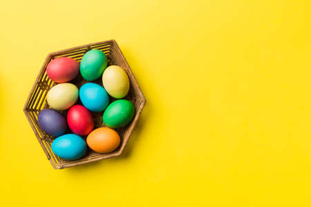 Multi colors Easter eggs in the woven basket on colored background . Pastel color Easter eggs. holiday concept with copy space.の写真素材