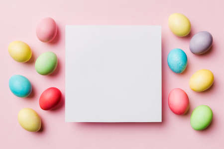 round frame multicolored Easter eggs with white blank paper on a brown background, close-up, space for text, blank for design, selective focus, tinted image.の写真素材