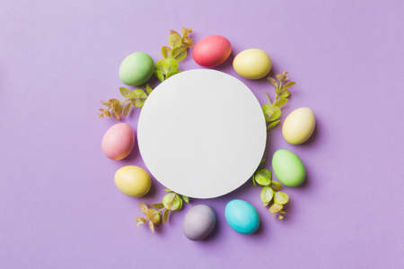 round frame multicolored Easter eggs with white blank paper on a brown background, close-up, space for text, blank for design, selective focus, tinted image.の写真素材