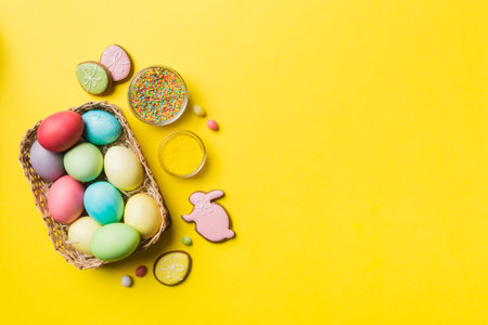 Colorful easter cookies in basket with Multi colors Easter eggs on colored background . Pastel color Easter eggs. holiday concept with copy space.の写真素材