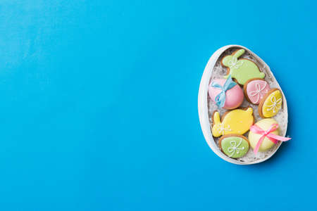 Colorful easter cookies in basket with Multi colors Easter eggs on colored background . Pastel color Easter eggs. holiday concept with copy space.の写真素材