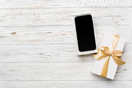 Opened gift box with gold ribbon and smartphone on color background, top view. Blank open box packaging mockup , Template for your design - branding mockup.の写真素材