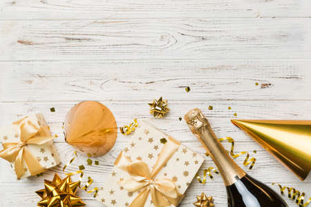 Flat lay composition of Champagne bottle gift box ribbons and confetti on colored background. Flat lay, top view holiday concept.の写真素材