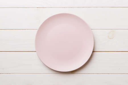 Top view of empty pink plate on wooden background. Empty space for your design.の写真素材