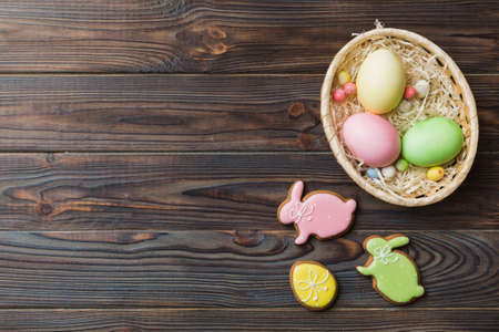 Colorful easter cookies in basket with Multi colors Easter eggs on colored background . Pastel color...