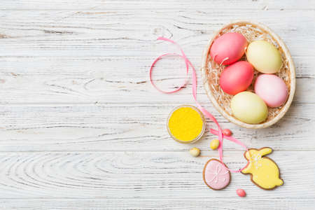 Colorful easter cookies in basket with Multi colors Easter eggs on colored background . Pastel color...