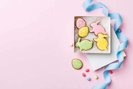 Colorful easter cookies in basket with Multi colors Easter eggs on colored background . Pastel color...
