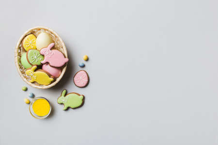 Colorful easter cookies in basket with Multi colors Easter eggs on colored background . Pastel color...