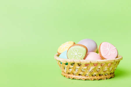 Colorful easter cookies in basket with Multi colors Easter eggs on colored background . Pastel color Easter eggs. holiday concept with copy space.の写真素材
