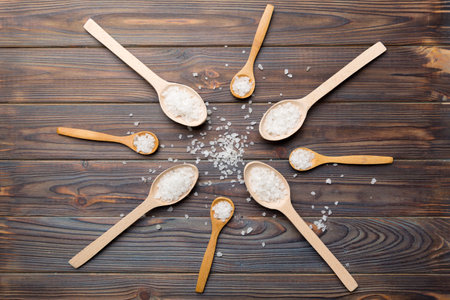 salt on wooden spoon on wood background. Spoons with different salt.