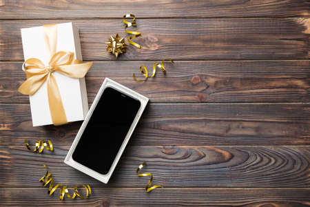 Opened gift box with gold ribbon and smartphone on color background, top view. Blank open box packaging mockup , Template for your design - branding mockup.の写真素材